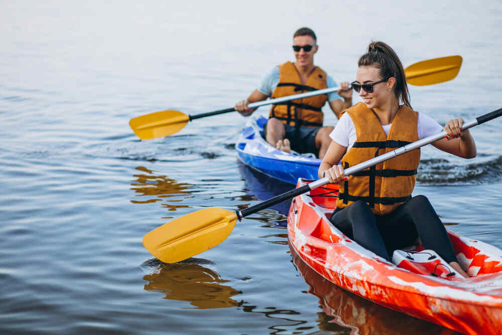 Two guests paddling kayaks on calm water