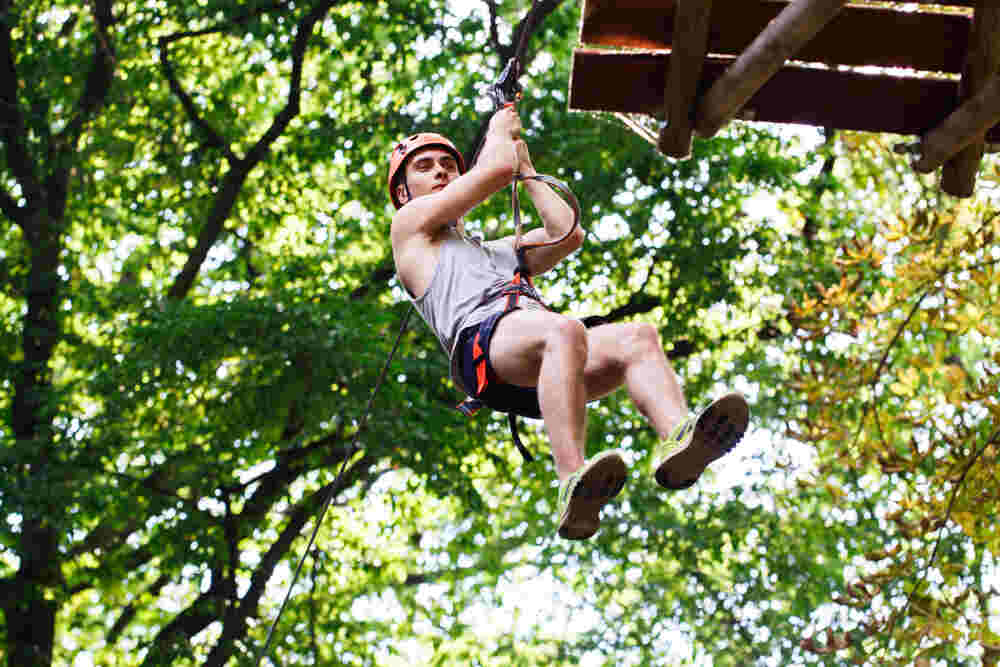 Guest on a zip line above the rainforest canopy